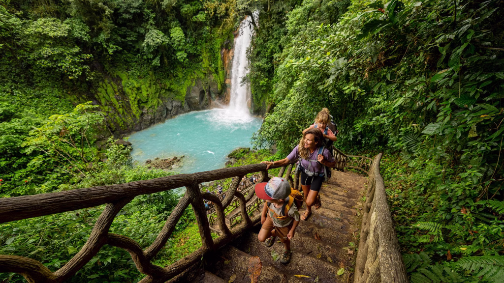 family hiking up stairs in Costa Rica next to a waterfall